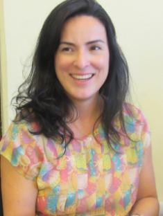 Headshot of Dr Marília Luz David, wearing a pink, blue and yellow short sleeved top